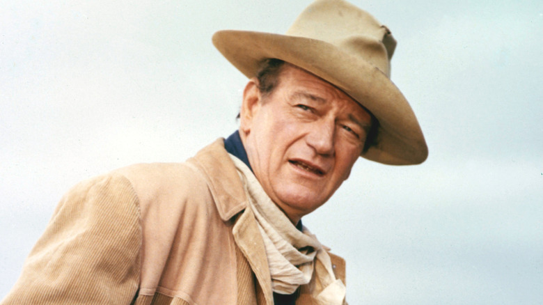 John Wayne leans forward and squints