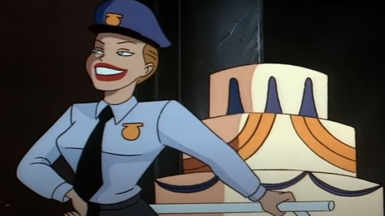 Harley Quinn in a police costume pushing a giant cake