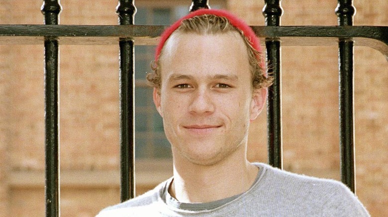 Heath Ledger smiling in front of fence