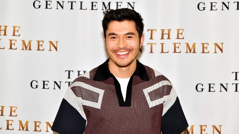 Henry Golding smiling while promoting The Gentlemen 