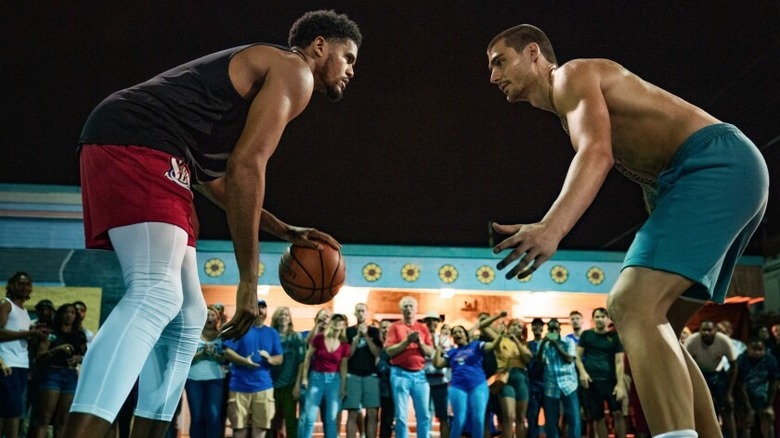 2 men playing basketball with a crowd