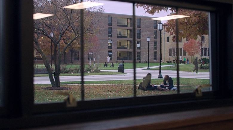 Wide shot looking out window at people sitting in grass