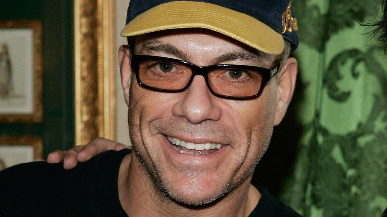 Jean-Claude Van Damme in hat and sunglasses smiling