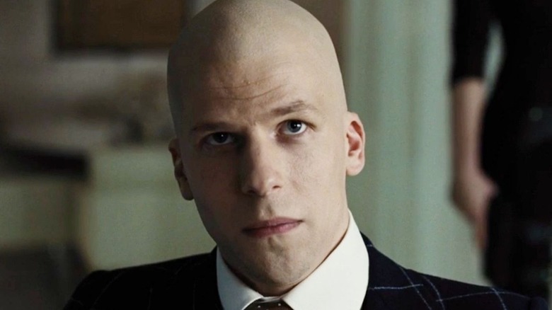 Lex Luthor wearing a suit and sitting in a chair