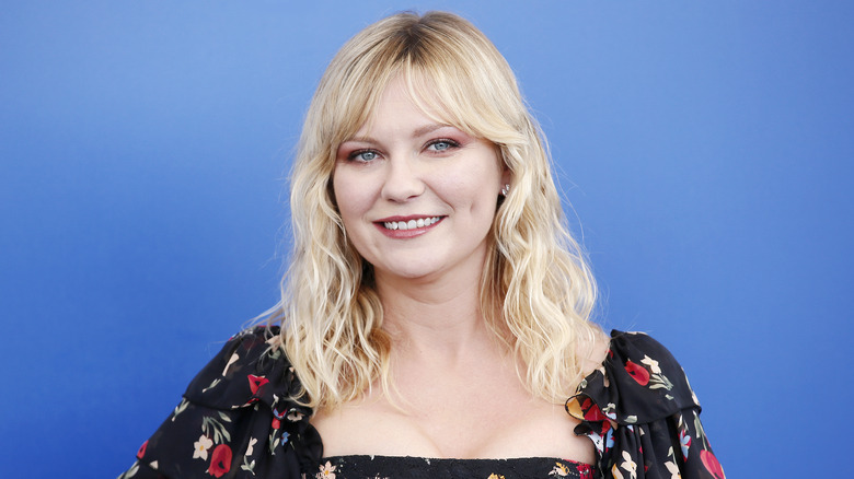 Dunst smiling in front of blue backdrop