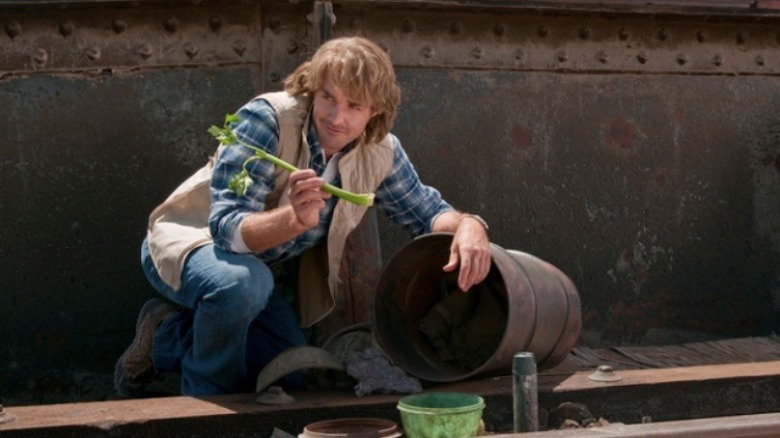 MacGruber crouches and holds a piece of celery