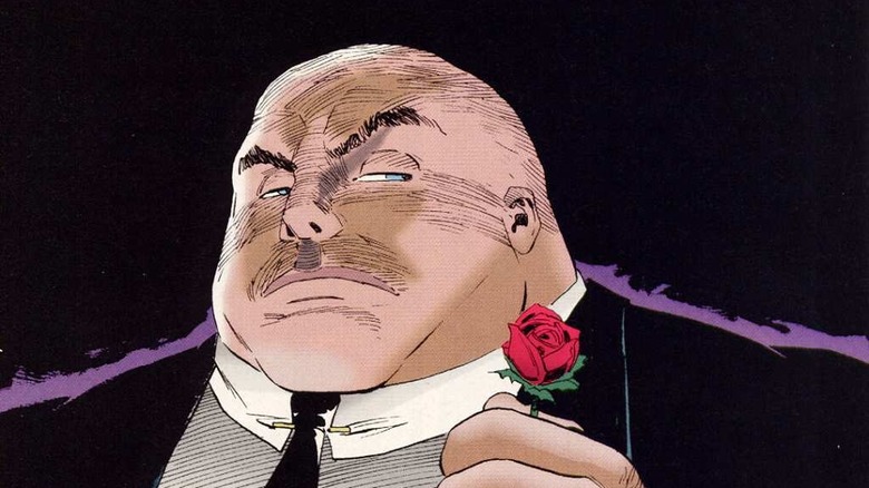 The Kingpin in black holds rose