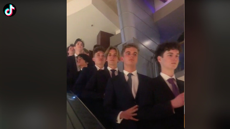 Teenage guys dressed in suits riding an escalator