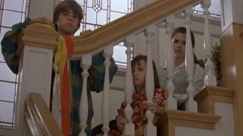 Chris, Natalie, and Lydia peering solemnly through banister