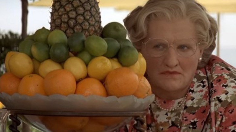 Mrs. Doubtfire scowling behind bowl of fruit