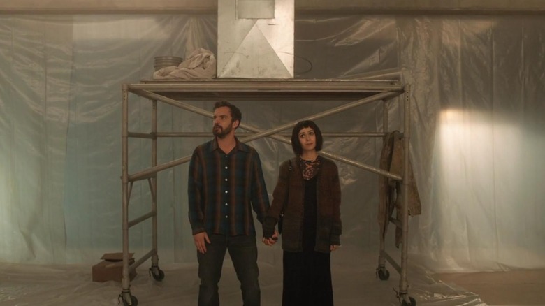 Jake Johnson and Cristin Milioti hold hands in an unfinished room