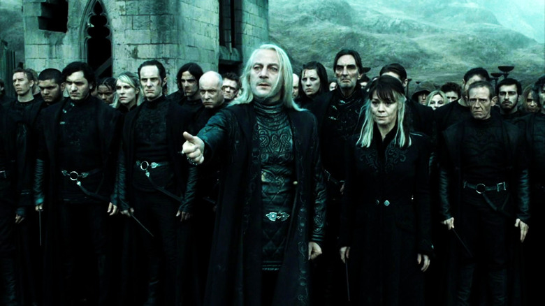 Narcissa Malfoy and Lucius Malfoy standing with Death Eaters