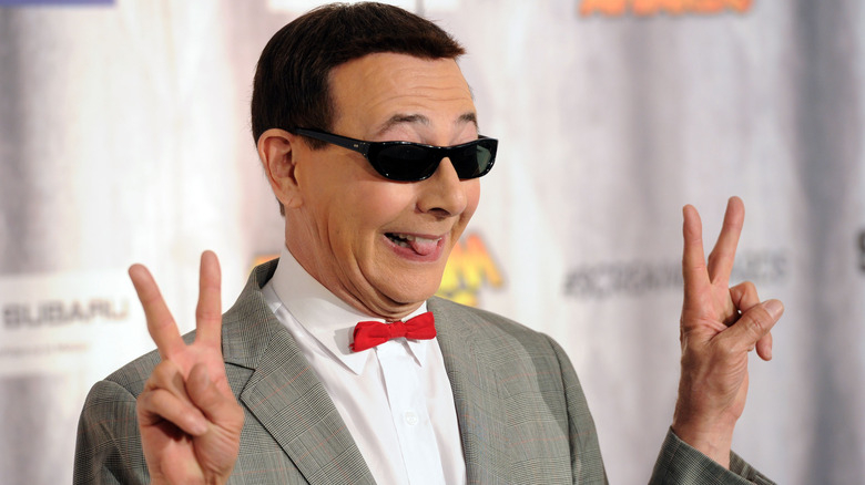 Pee-wee Herman makes peace signs wearing sunglasses