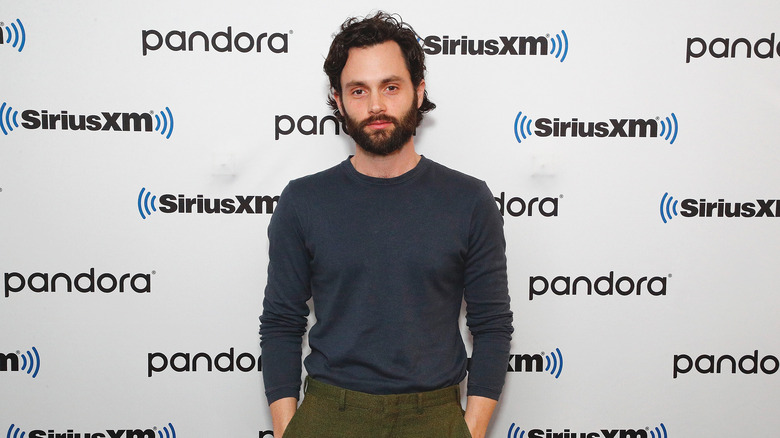 Penn Badgley standing with his hands in his pockets