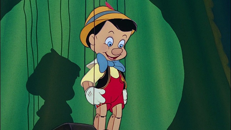 Pinocchio with strings on stage smiling