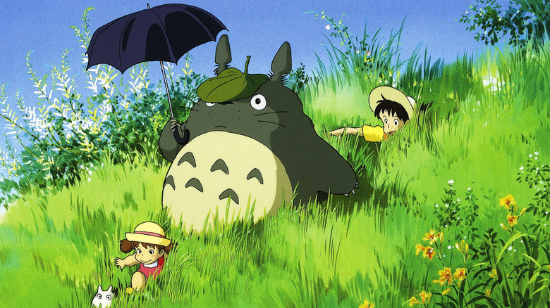 Two kids and big Totoro in grassy field 