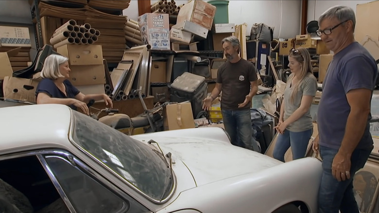 Four people standing by vintage Porsche