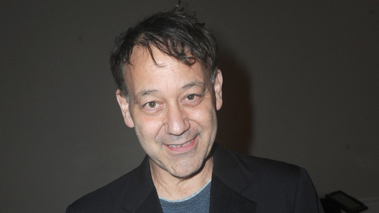 Sam Raimi smiles black background