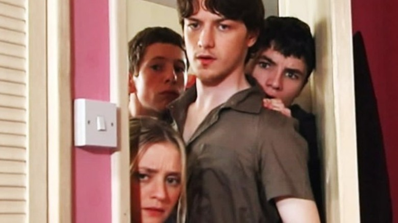 Four young people nervously through a doorway