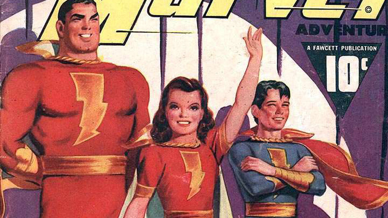 Captain Marvel stands next to waving young girl and boy with arms crossed