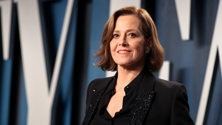 Sigourney Weaver smiling in a black suit