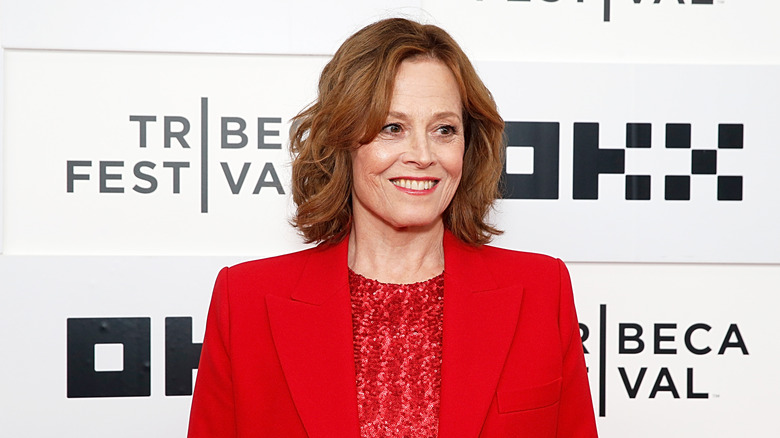 Sigourney Weaver smiling in a red jacket