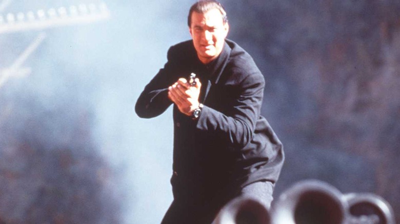 Under Siege 2: Dark Territory's Steven Seagal holding gun in crouching position