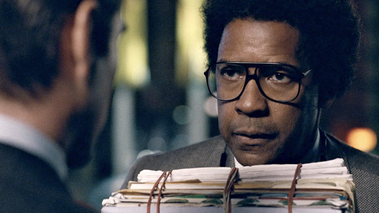 Denzel Washington as Roman J. Israel, Esq. holding a stack of papers