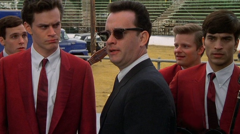 The Wonders in red suits looking at Tom Hanks in sunglasses