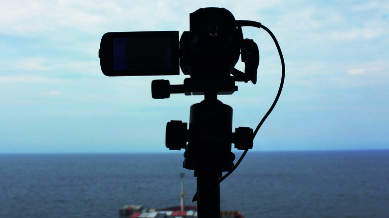 Camera filming freighter on sea