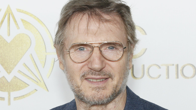 Liam Neeson in glasses smiling