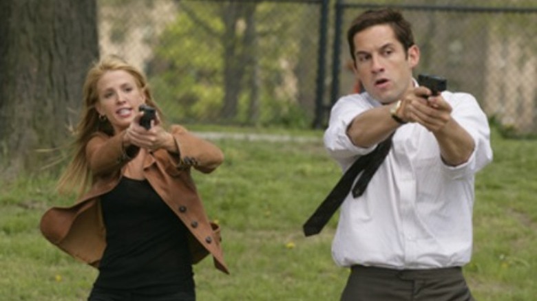 Enrique Murciano and Poppy Montgomery aiming guns