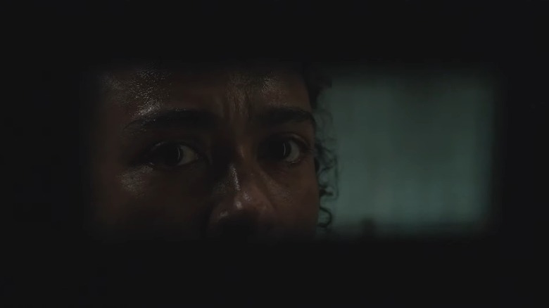 Connie looking through a hole in a wall