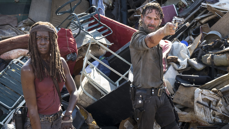 Michonne and Rick hoisting their weapons at the garbage dump