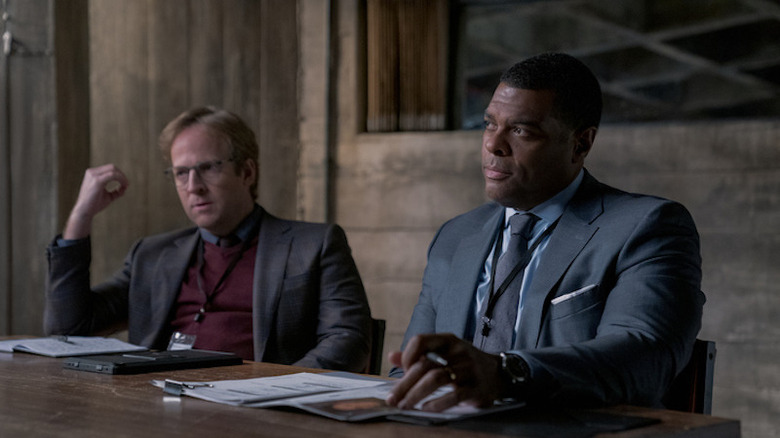 Dr. Faber sitting next to Young in interrogation room 