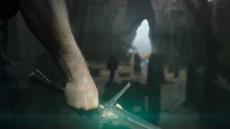 Geralt's fist holding sword lighting up green