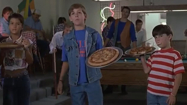 Three kids holding pizzas