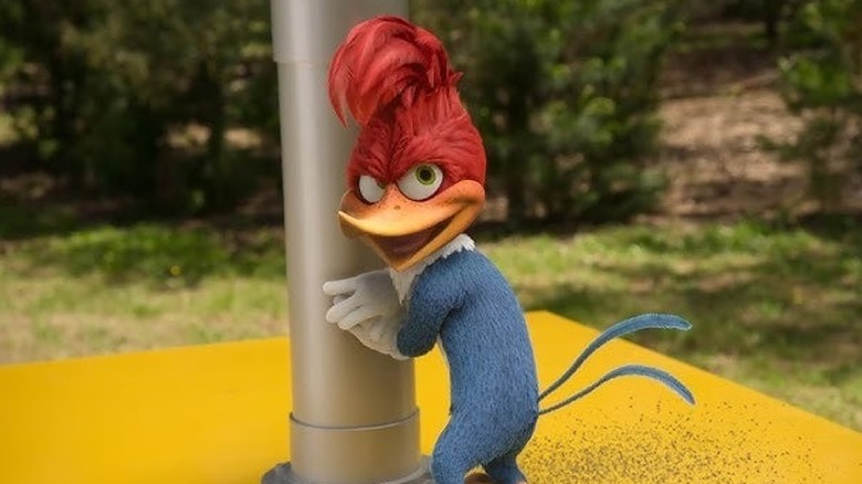 Woody Woodpecker leaning against a pole with a devious grin on his face