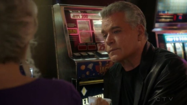 Ray Liotta sitting next to slot machine