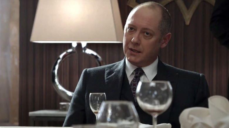 Red Reddington sitting at a table