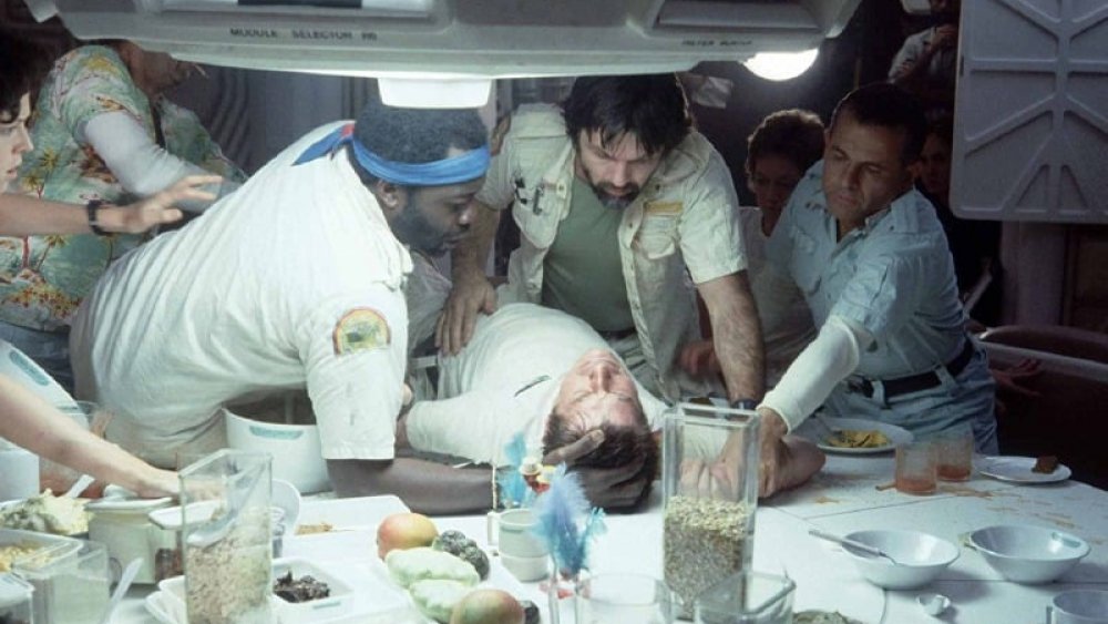 The crew of the Nostromo, moments before the alien erupts from Kane's chest, in Alien