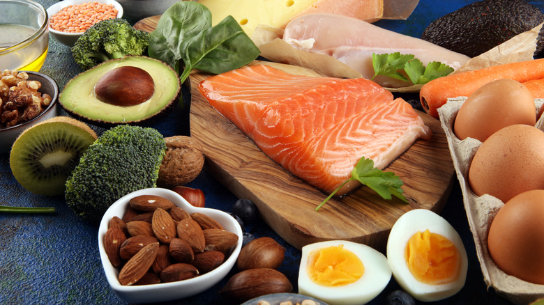 Salmon, nuts, eggs and fresh produce displayed on a wooden cutting board