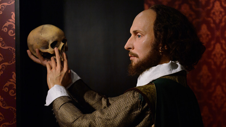 A wax statue of William Shakespeare posing with a skull