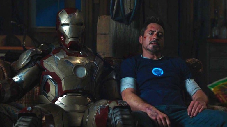 Tony sits with his armor on a couch