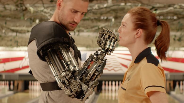 Charlie examines a bionic arm in front of Poppy