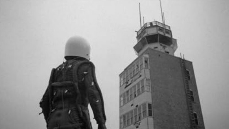 Spacesuited man looks at tower