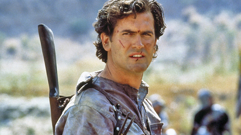 Bruce Campbell Ash Williams scowling shotgun