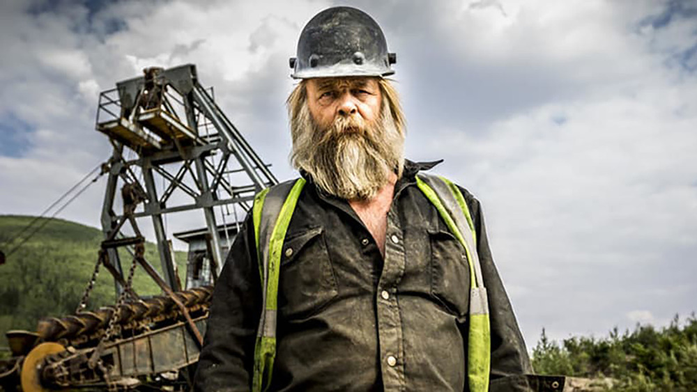 Tony Beets looking into the camera with a helmet on and mining machinery in the background