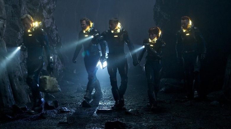 The crew walking through cave with flashlights 