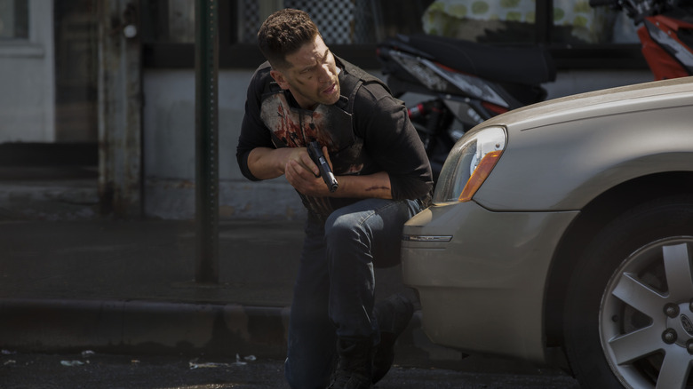 The Punisher crouched behind car